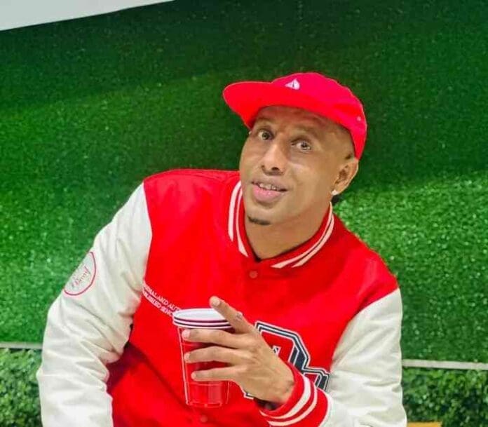 A man in a red and white varsity jacket and red cap holds a red plastic cup, posing in front of a green artificial grass background—just like the vibe of DJ Ace's Private School Piano Mix, Episode 20.