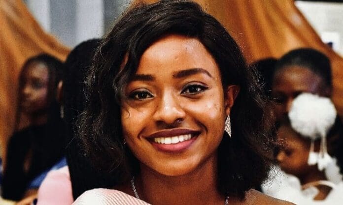 A woman with short, wavy black hair and a light pink top smiles at the camera, with several people blurred in the background—capturing Grace Grandi’s optimism for Africa's music future.