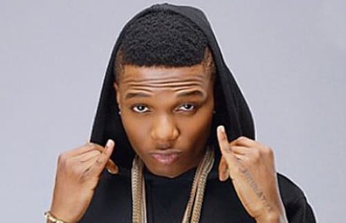 A person wearing a black hoodie over their head, looking directly at the camera and holding the hoodie strings with both hands—a pose reminiscent of Wizkid fans channeling confidence amid ongoing Fela comparisons.