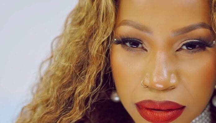 Close-up of a woman with long curly hair, defined eyebrows, false eyelashes, bold red lipstick, and a gold nose ring, perfect for an OkayAfrica feature on East African music trends in October 2025.