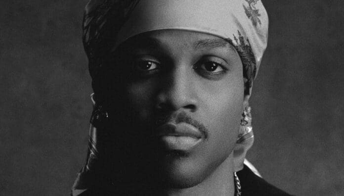 A person wearing a patterned headscarf and earrings looks directly at the camera in a black and white portrait with a dark background, exuding the confidence often seen in Afrobeats artists from Mavin Records.