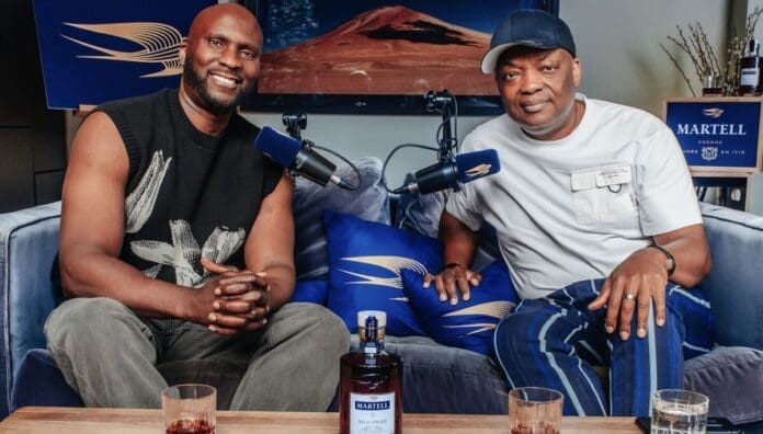 Two men sit on a blue couch with microphones, Martell cognac bottle and glasses on the table, branded decor in the background—capturing DJ Abass’s signature Swift Conversations and promoting Pan-African visibility.