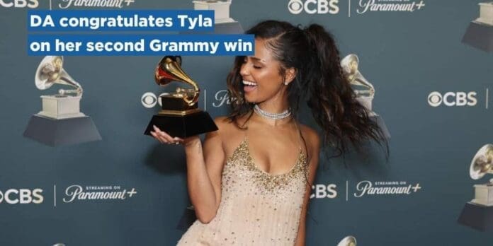 1770325808_Tyla.jpg Tyla, in a light dress, smiles while holding her Grammy trophy, standing in front of a backdrop with CBS and Paramount+ logos, celebrating her Grammy win.