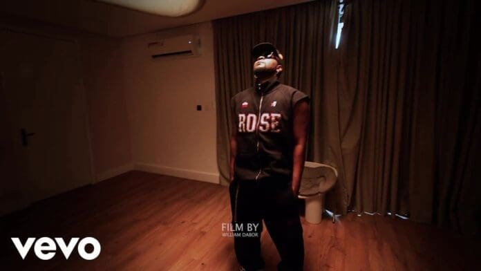A person wearing a sleeveless "ROSE" vest and cap stands in a dimly lit room with wood flooring and beige curtains. "Vevo", "Film by William Dabor," and "Kizz Daniel Lyric Video" text appears on the image.