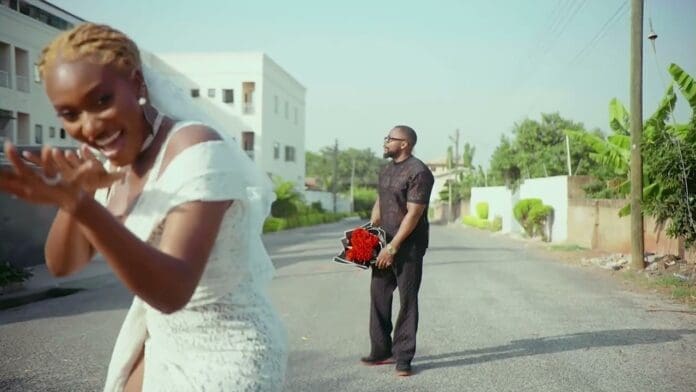 A man and woman walk down a street in the Official Visualizer for "Too Late" by Wendy Shay.
