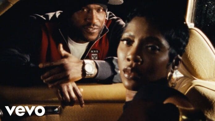 A man leans against a car window, looking in, while a woman sits in the driver’s seat, facing the camera. The vintage, grainy effect sets the mood for “On The Low” by Tiwa Savage. The Vevo logo is visible in the corner.