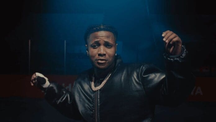 A person in a black leather jacket and chain necklace poses with their arms raised under blue lighting, echoing the bold style of Girl On FYA.