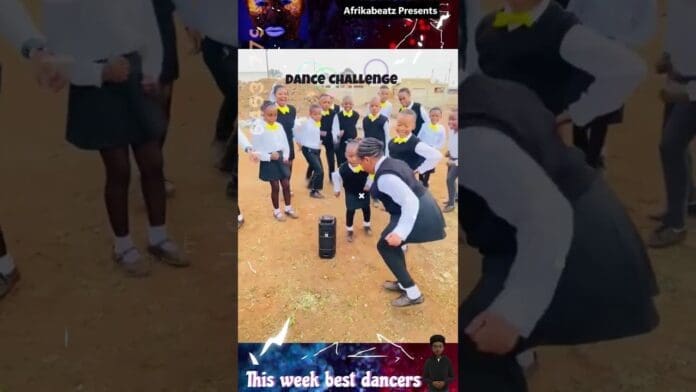 A group of school children in uniform participate in a lively Dancechallenge outdoors, moving to Magumba Amapiano 2025, with a speaker placed on the ground in the center.