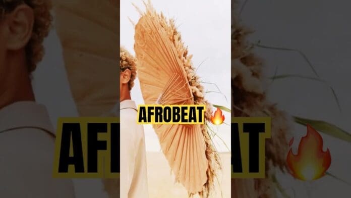 A person holds a large dried palm leaf umbrella with the words “top Afrobeat” and a fire emoji overlaid in bold yellow text, capturing the vibrant spirit of the best Afrobeat 2025.