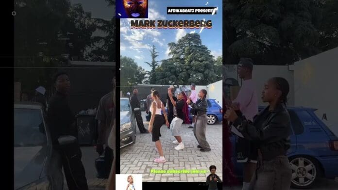 A group of people join a lively Amapiano dancechallenge outdoors near parked cars, while others stand nearby watching and recording on their phones.