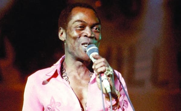 An African man, inspired by Fela Kuti and his Grammys Lifetime Achievement Award, singing passionately into a microphone.