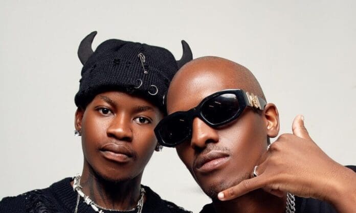 Two men pose together; one rocks a black hat with horn details and jewelry, while the other wears sunglasses and flashes a 'call me' hand sign—perfect vibes for Amapiano weekend hits.