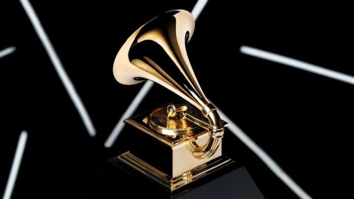 A gold Grammy Award trophy shaped like a gramophone sits on a black base against a dark background with white diagonal streaks, reflecting the prestige celebrated by both Grammy insiders and global Afrobeats artists.