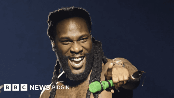 A man with long braids smiles and points while holding a green microphone on stage. The BBC News Pidgin logo is visible in the corner, as highlights from the Afrima awards 2026 and winners list are discussed.