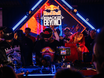 A crowded DJ booth with performers and attendees under colorful lights, as a "Red Bull Back 2 Beyond" sign glows in the background—an electrifying scene brought to life in Durban with East Coast Radio’s vibrant presence.