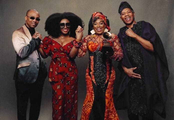 Four people stand together posing for a photo; one holds a Fela Grammy Lifetime Achievement Award. They are dressed in colorful, formal outfits and smiling at the camera, celebrating music’s legacy featured on thisdaylive.com.