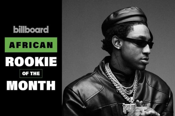 Black and white photo of a man in sunglasses, leather jacket, and chains next to text reading "billboard African Rookie of the Month," channeling Travis Scott vibes.