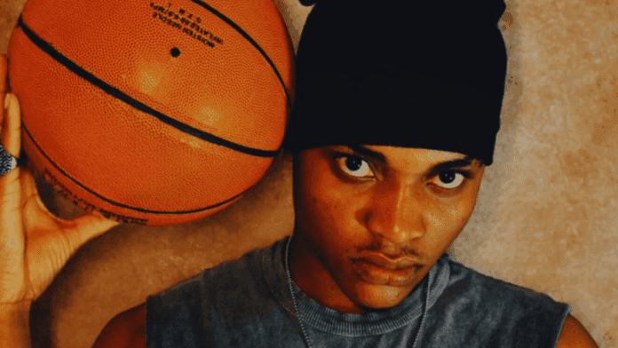Person wearing a black headwrap holds a basketball near their face and looks directly at the camera against a neutral background, channeling the confidence of "Nobody" by Vizco.