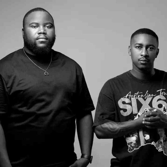 Two men stand side by side against a plain background, both facing the camera; one wears a solid black shirt, and the other sports a dark graphic T-shirt—capturing the essence of Maero's unique musical experience.