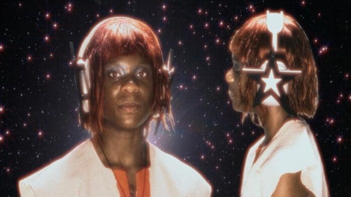 A cosmic lover with shiny makeup and a red wig wears star-shaped headphones, standing before a starry space backdrop—shown in both front and side views, inspired by Dreamer Isioma’s unique style.
