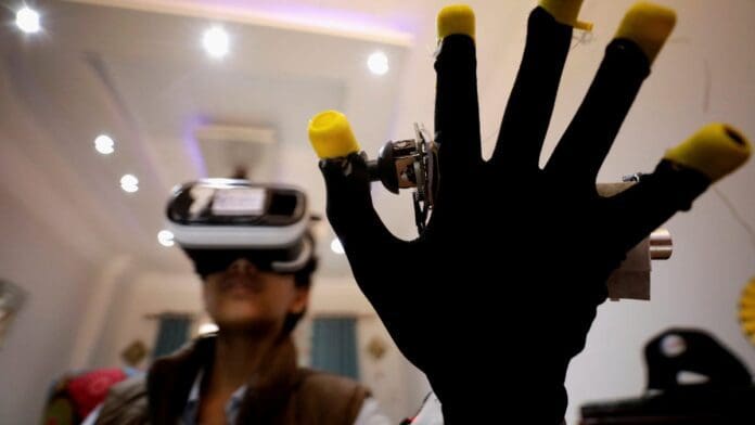 Person wearing a virtual reality headset holds up a gloved hand with digital tracking devices attached to the fingertips, immersed in MTN's metaverse concert - a testament to Africa's creative industry's technological prowess.