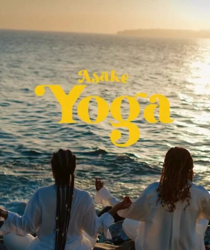 Two individuals practice yoga facing the ocean at sunset. The text 