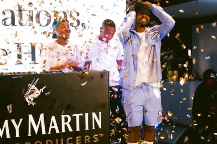 Three men celebrate on stage with confetti falling. One man on the right covers his eyes, while the others stand beside him, smiling. The background features a sign and branding for Rémy Martin, hinting at the rise of South Africa's next big music producer as covered by The Citizen.