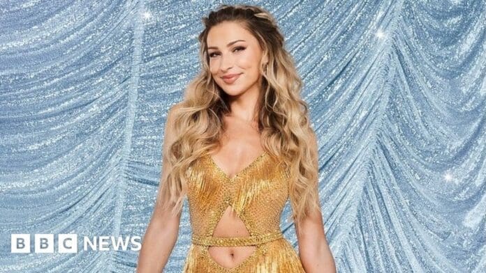 A woman in a gold dress is posing for BBC News at Strictly Come Dancing 2023.