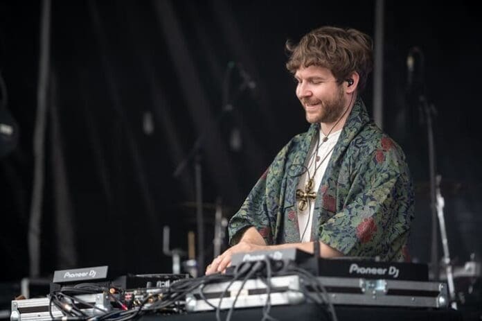 A DJ with a dj set performing at a festival.