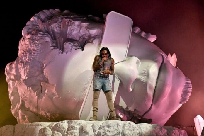 A woman standing on top of a large sculpture at Gunna's LA show.