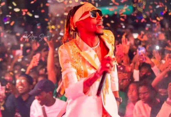 Zambian artist Yo Maps to perform in a white suit amidst confetti.