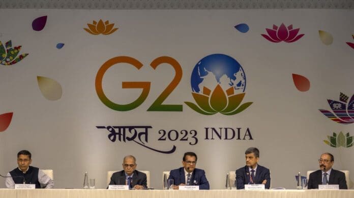 A group of men and women sitting at a table in front of a sign that says G20.