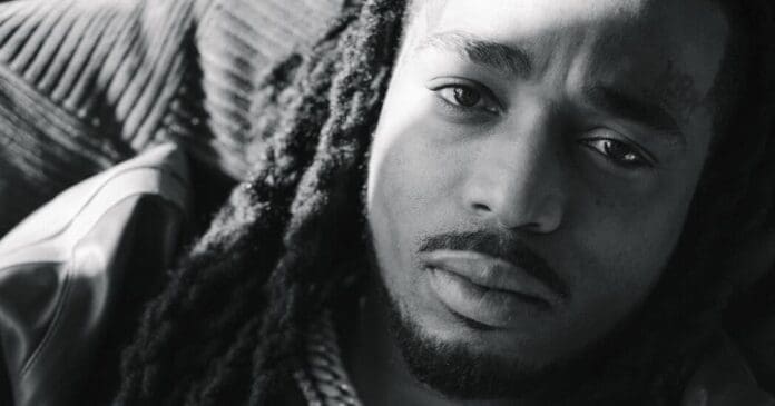 A black and white photo of a man with dreadlocks.