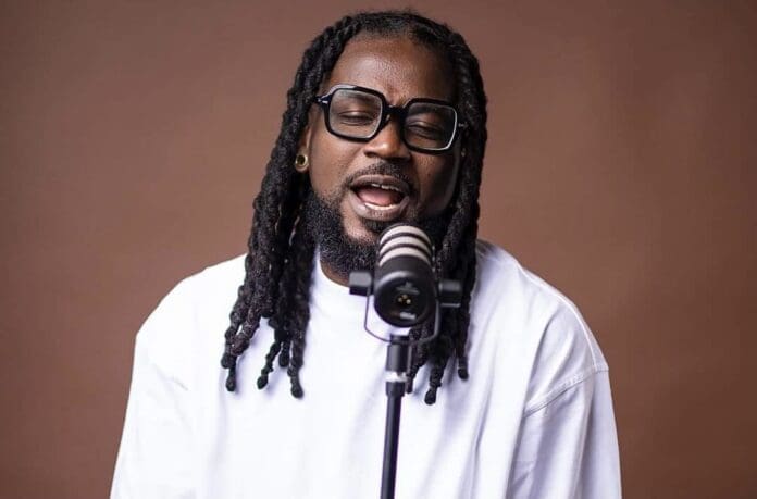 A man singing into a microphone with dreadlocks.