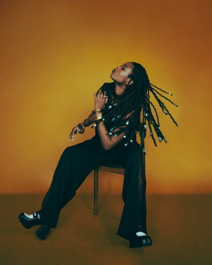 Lady Donli, a woman with dreadlocks, sitting on a chair during an interview for her latest album.