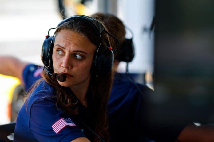 A woman in a headset is sitting in a car, passionately engrossed in motorsports.