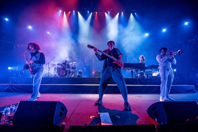 Ezra Collective performing a captivating gig at Royal Albert Hall, with bright lights illuminating the stage.