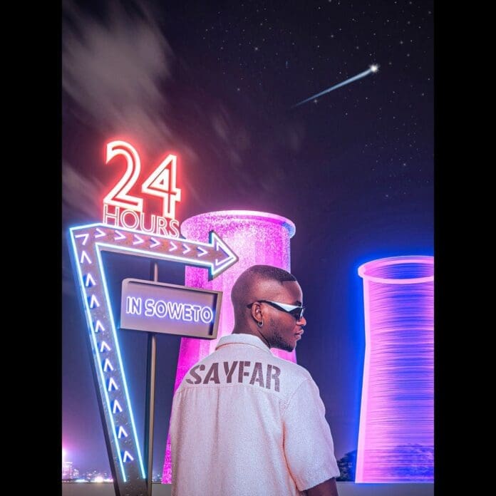 LeeMcKrazy, a man in a white shirt, standing in front of a neon sign.